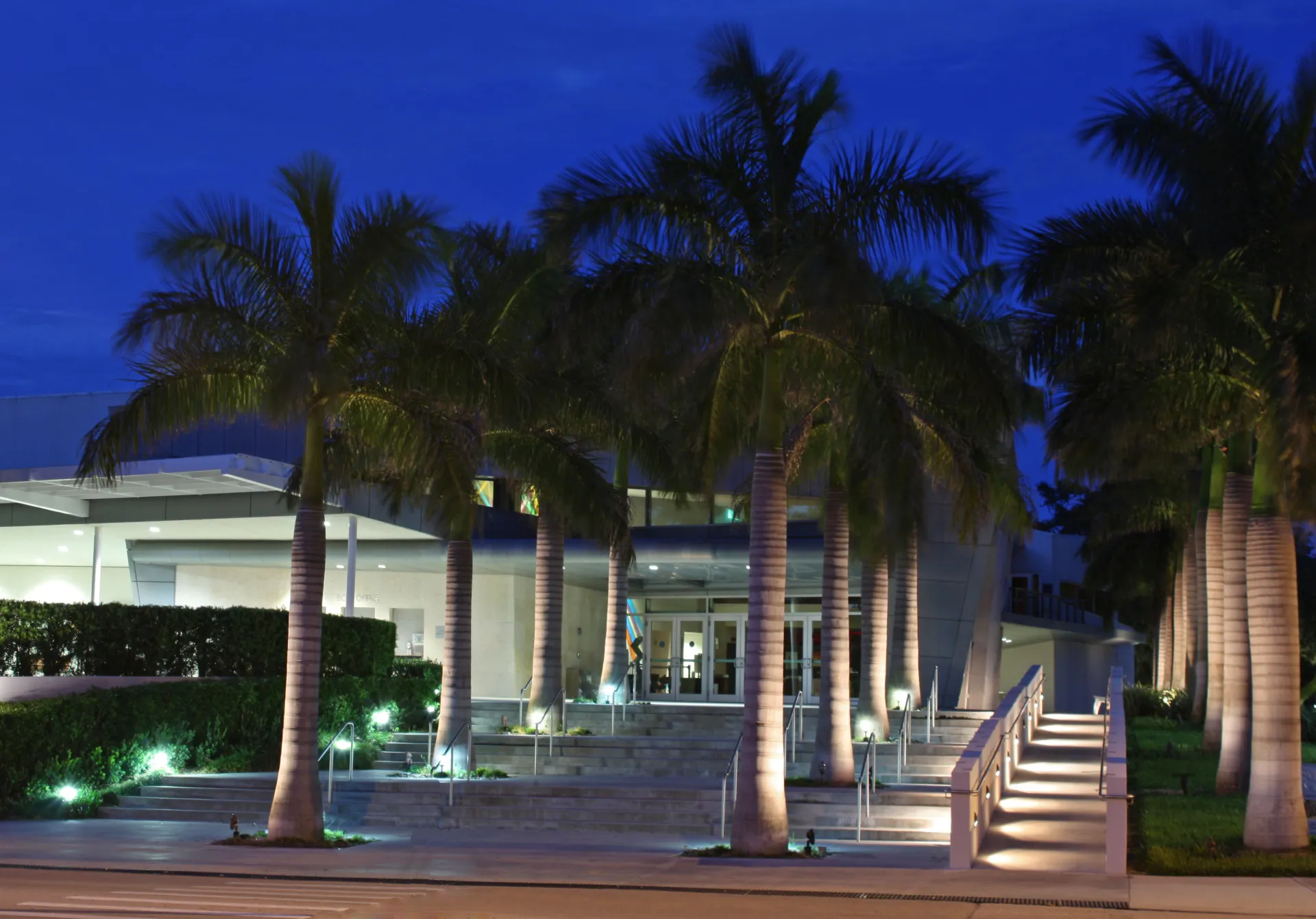 Riverside Theatre entrance framed by palm trees at dusk